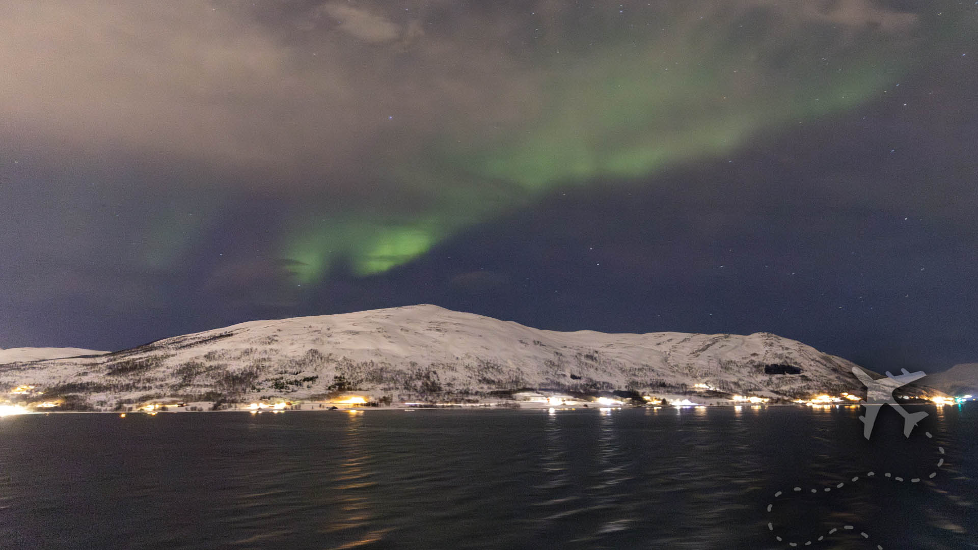 Northern lights visible above the mountains of Tromsø, Norway